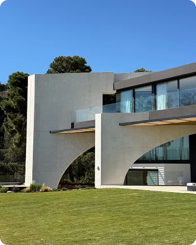 A modern villa with large arched openings in its facade, above a lawn